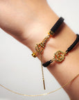 Close-up of a wrist wearing gold and black bracelets with a visible brand logo.