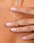 Gold necklace with a pendant held by a hand on a skin background