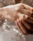 Close-up of a hand wearing engagement ring with a diamond on a blurred background