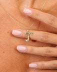 Gold necklace with a pendant held by a hand against skin background
