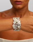 Close-up of a person wearing a decorative silver bracelet with pearls on a neutral background