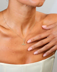 Woman wearing a gold necklace with a small pendant on a neutral background