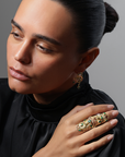 Woman wearing a gold ring with gemstones against a gray background