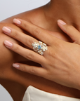 Close-up of a hand wearing a decorative ring with a blue gemstone on a neutral background