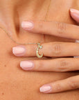 Gold necklace with a C pendant on a person's hand.