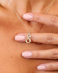 Gold necklace with a 'S' pendant on a person's chest.