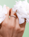 Hand wearing a ring with white flowers on a light green background