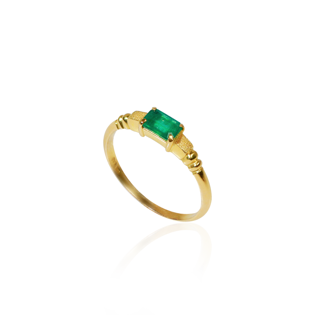 Gold ring with a green gemstone on a white background