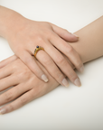 Close-up of a hand wearing a gold ring with a black gemstone on a white background