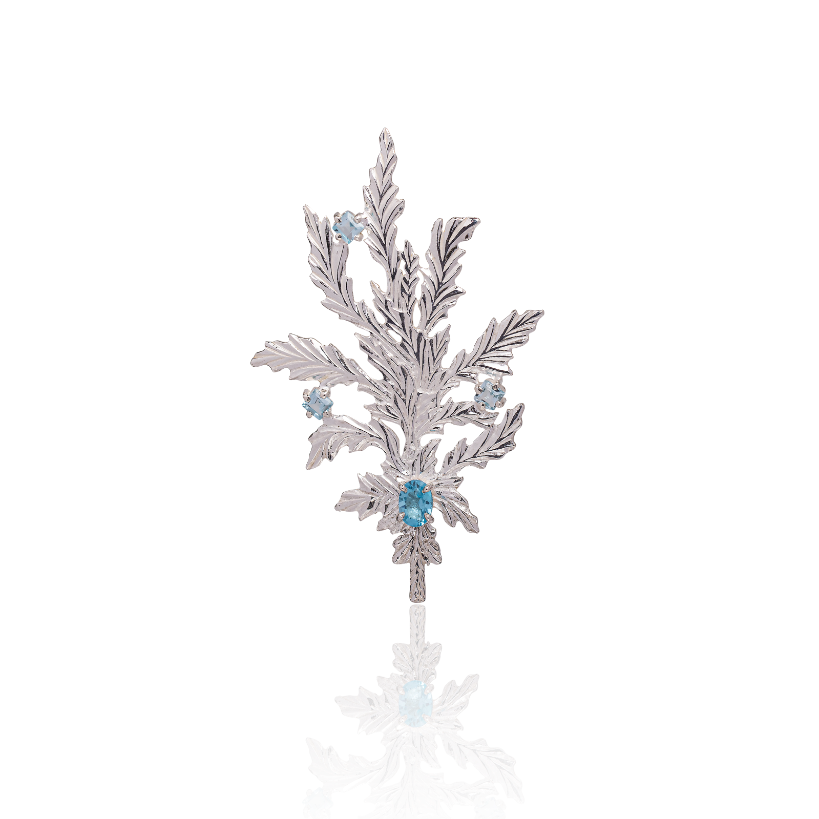 Silver leaf-shaped brooch with blue gemstones on a white background