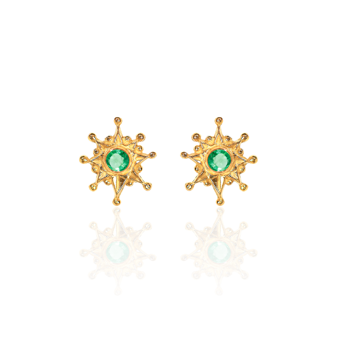Gold sun-shaped earrings with green gemstones on a white background