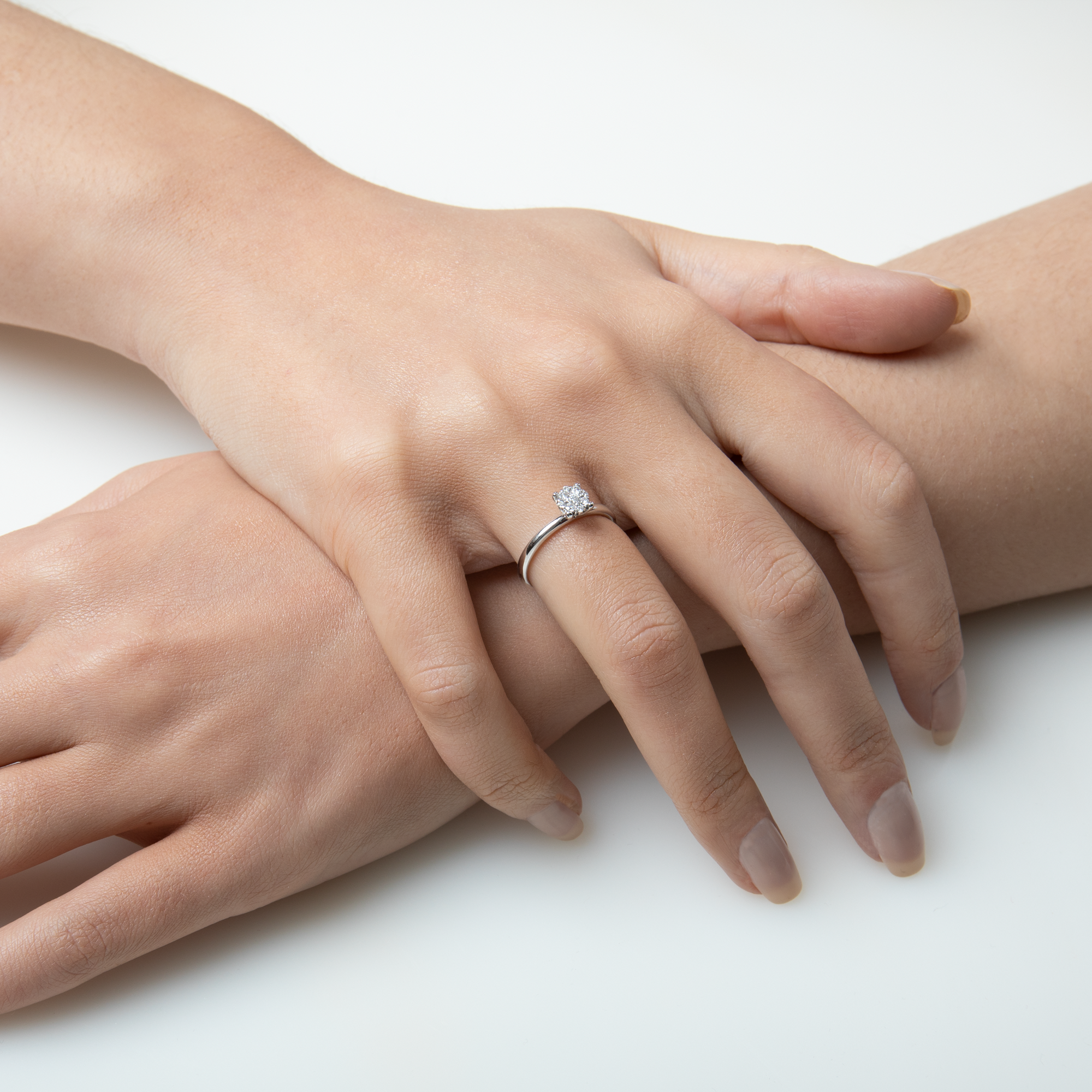 Close-up of two hands with a ring on a white background
