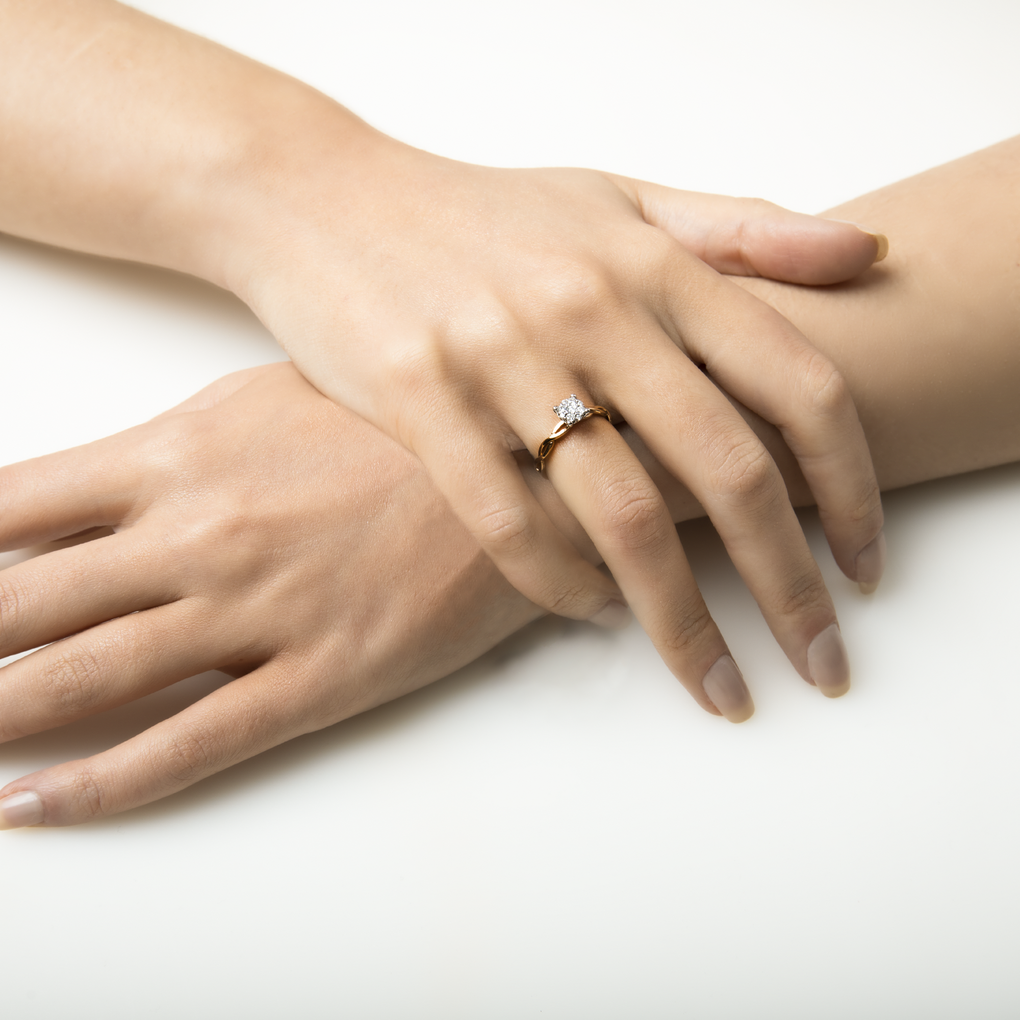Close-up of a hand wearing a diamond ring on a white background