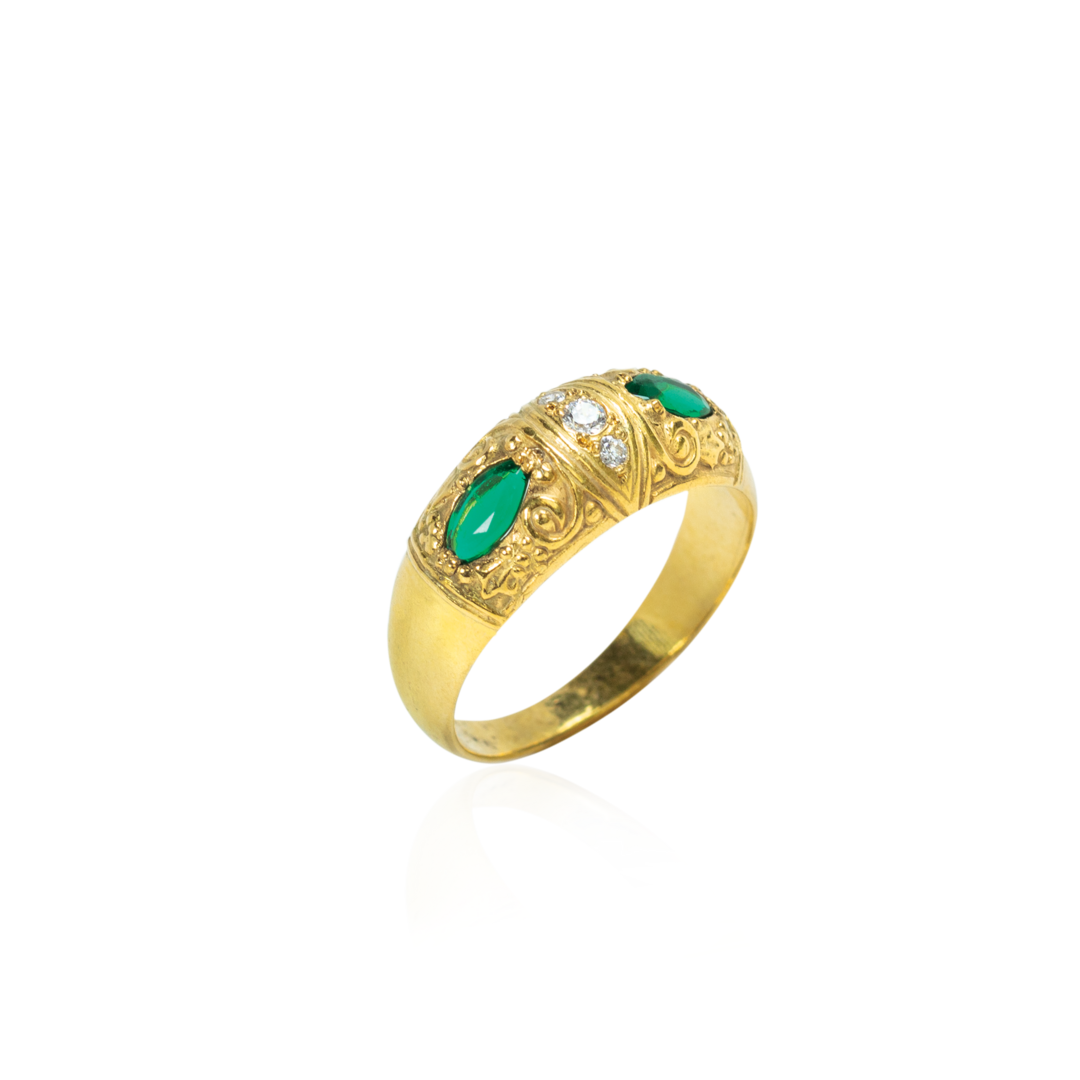 Gold ring with green gemstones and diamond accents on a white background