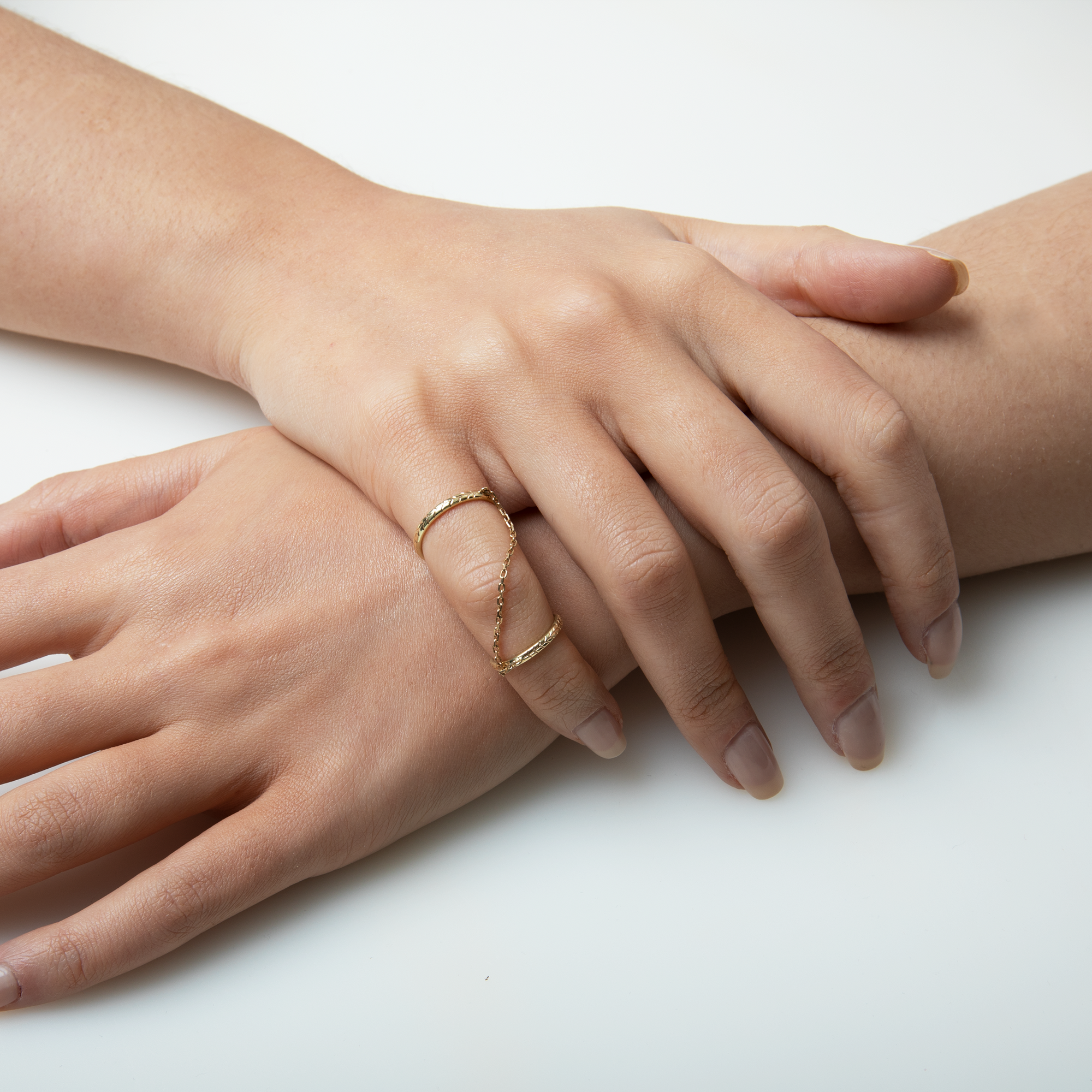 Two hands with gold rings on a white background