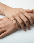 Two hands with gold rings on a white background