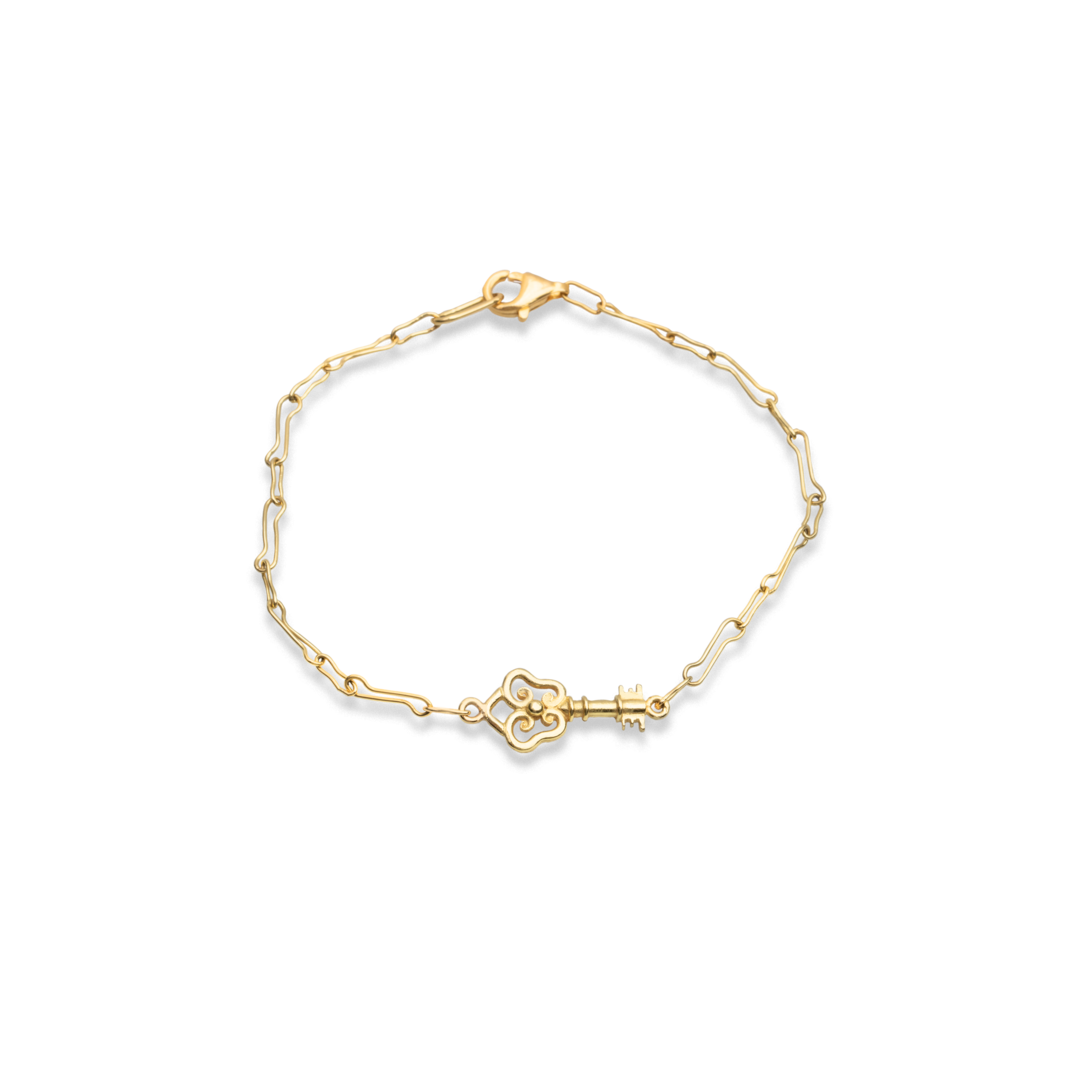 Gold bracelet with a key-shaped clasp on a white background