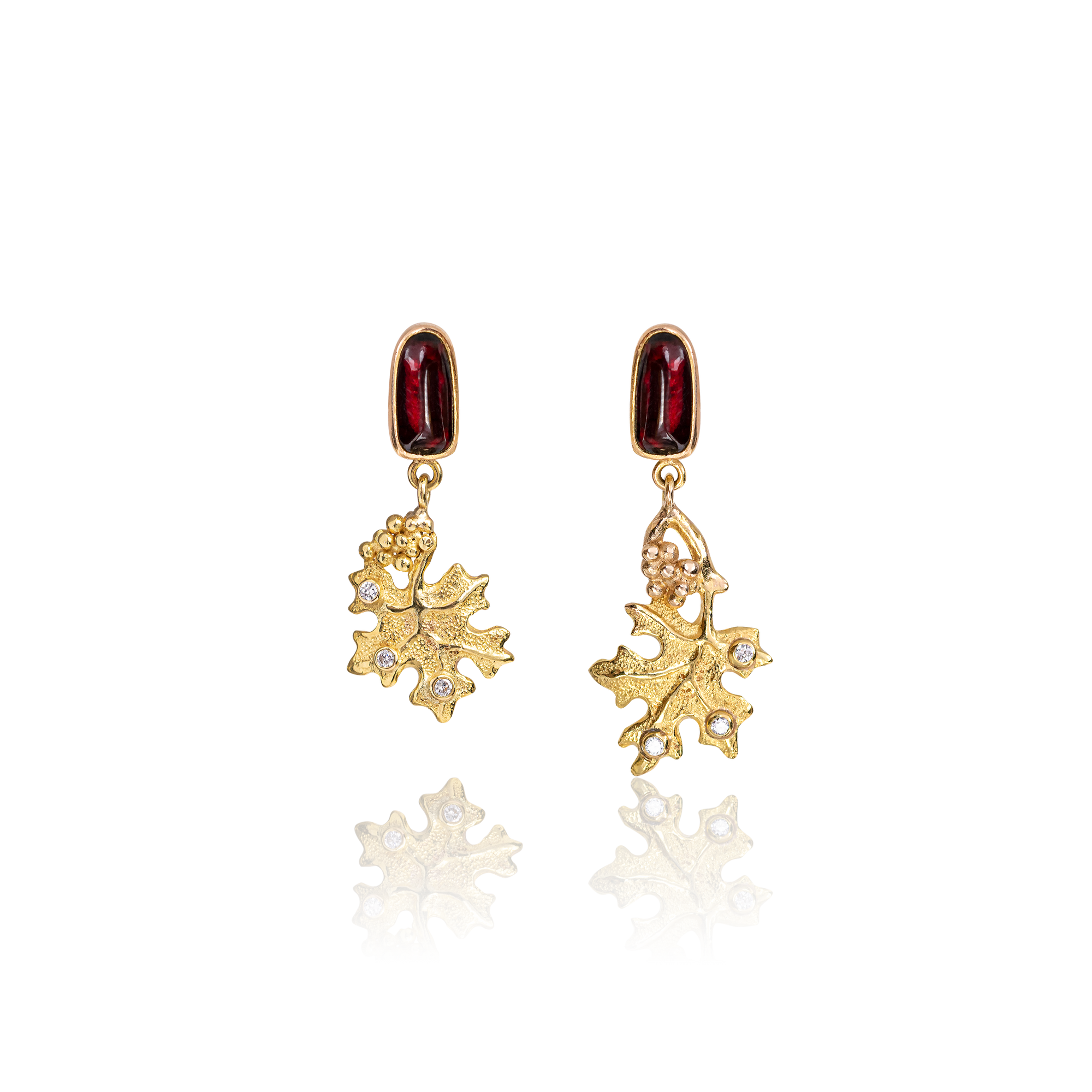 Gold leaf-shaped earrings with red gemstones on a white background