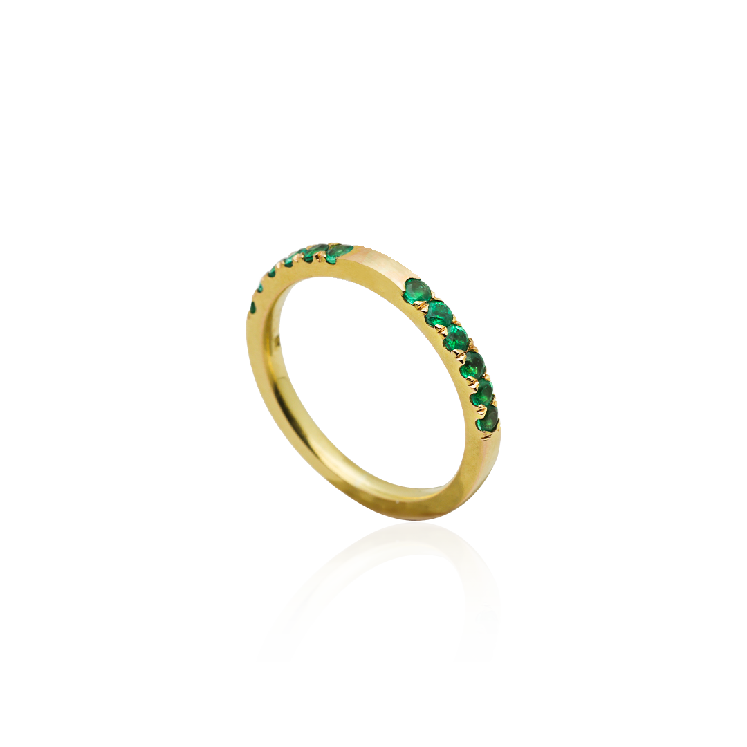 Gold ring with green gemstones on a white background
