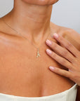 Gold necklace with a letter 'A' pendant worn by a person, with a hand touching the neck.