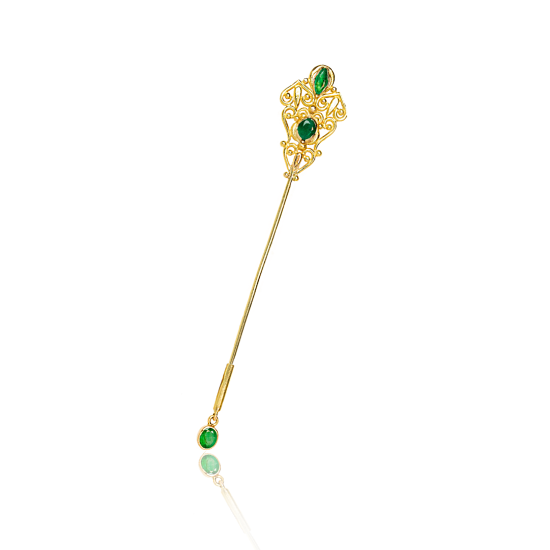 Gold brooch with green gemstones on a white background