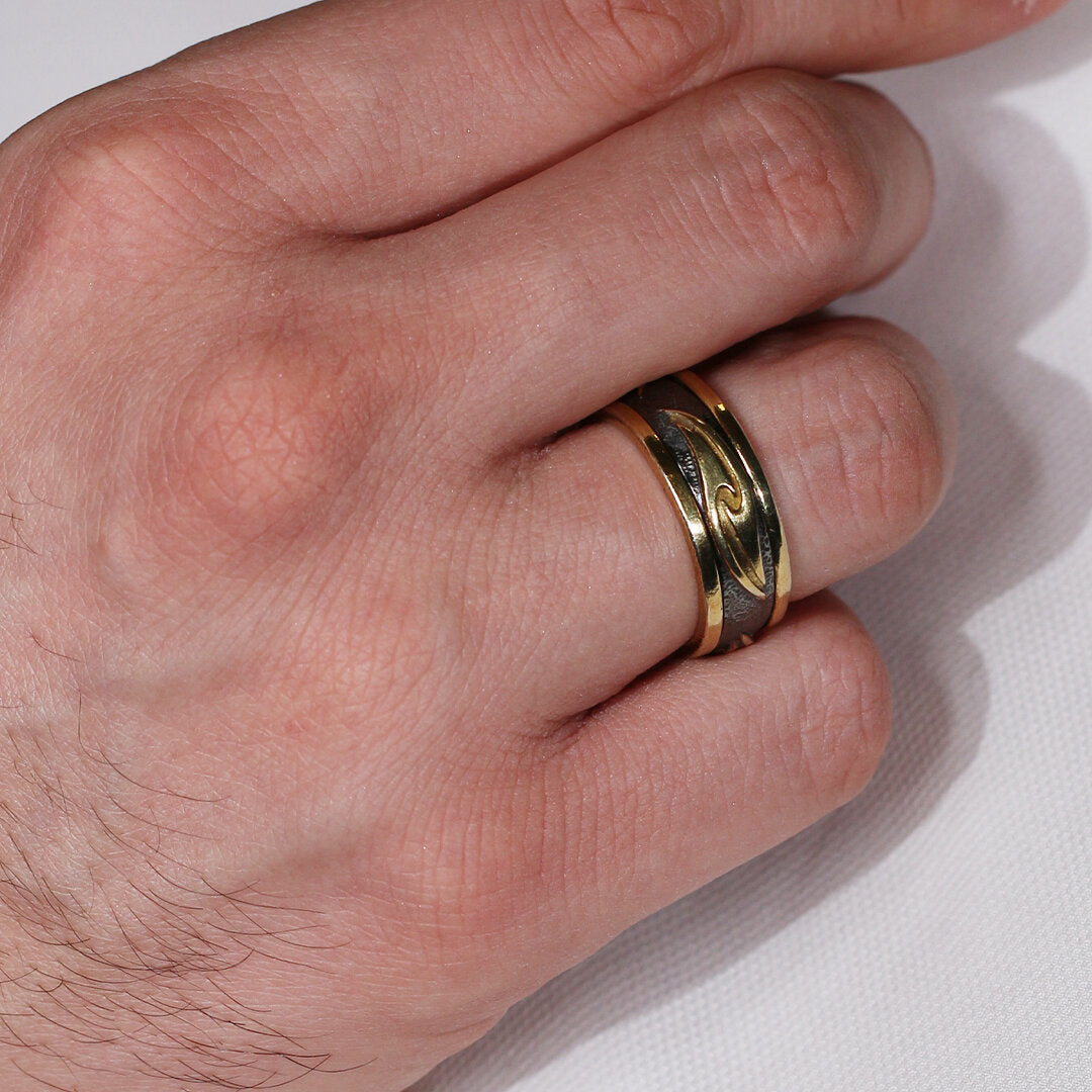 Hand wearing a gold ring on a light background