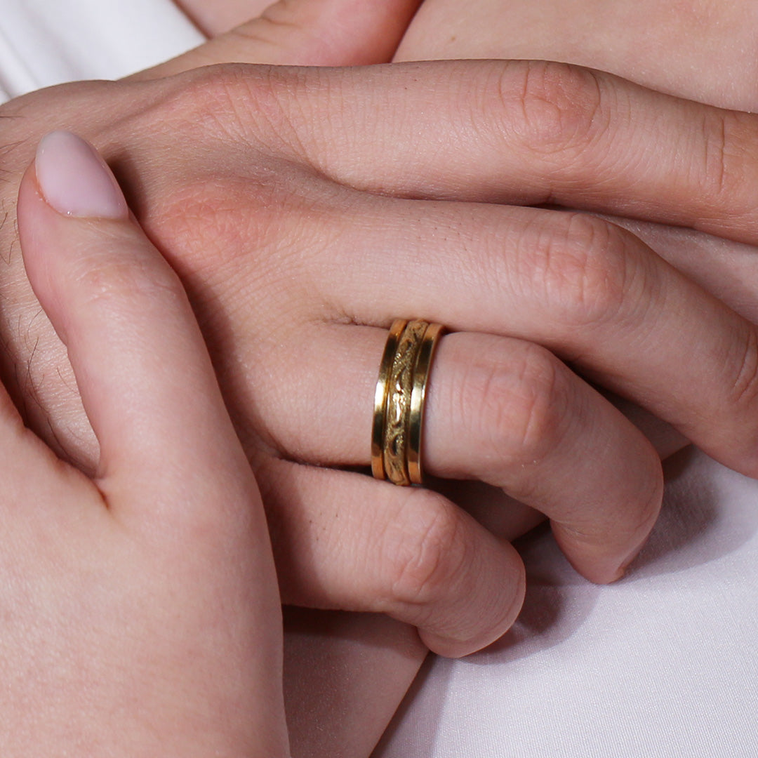 Close-up of a hand wearing a gold ring on a light background