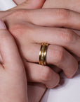 Close-up of a hand wearing a gold ring on a light background