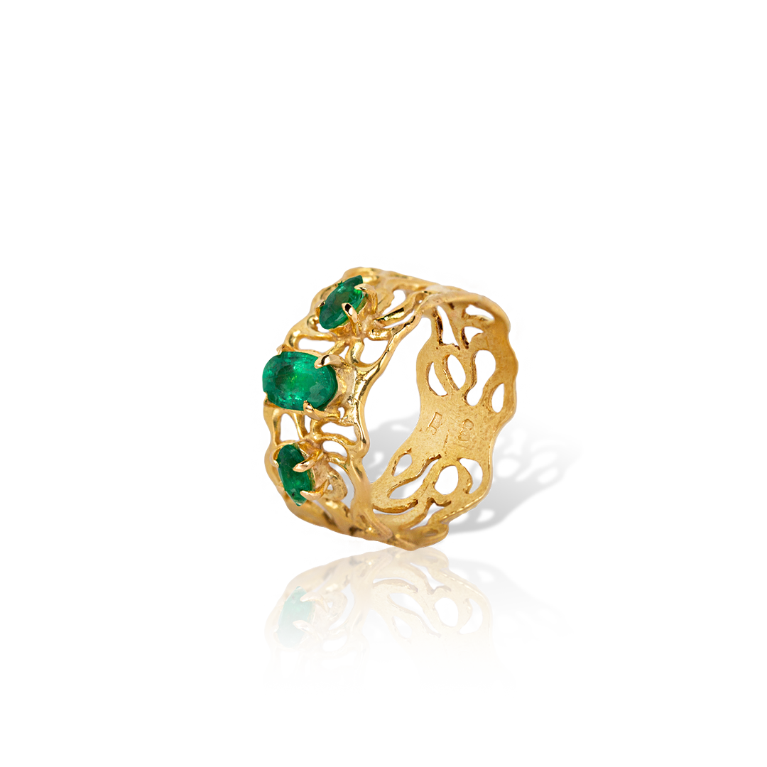 Gold ring with emerald stones on a white background