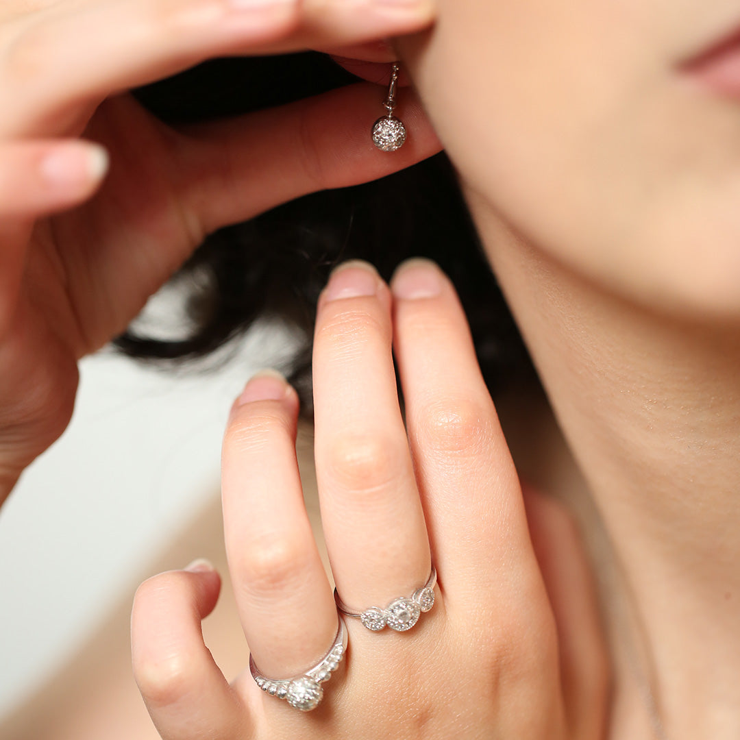 Close-up of a hand wearing two diamond rings with a blurred background