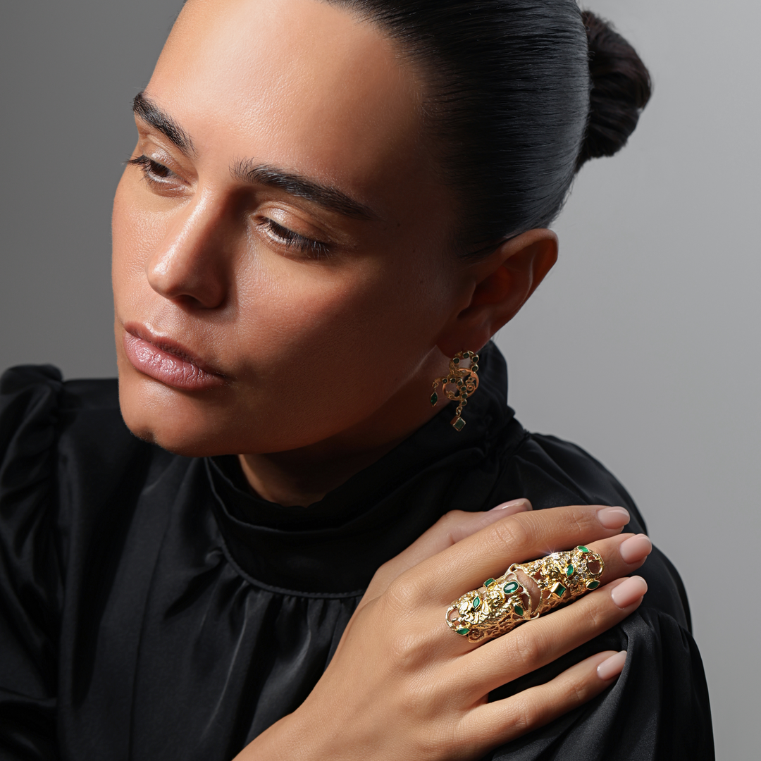 Woman wearing a gold ring with gemstones against a gray background