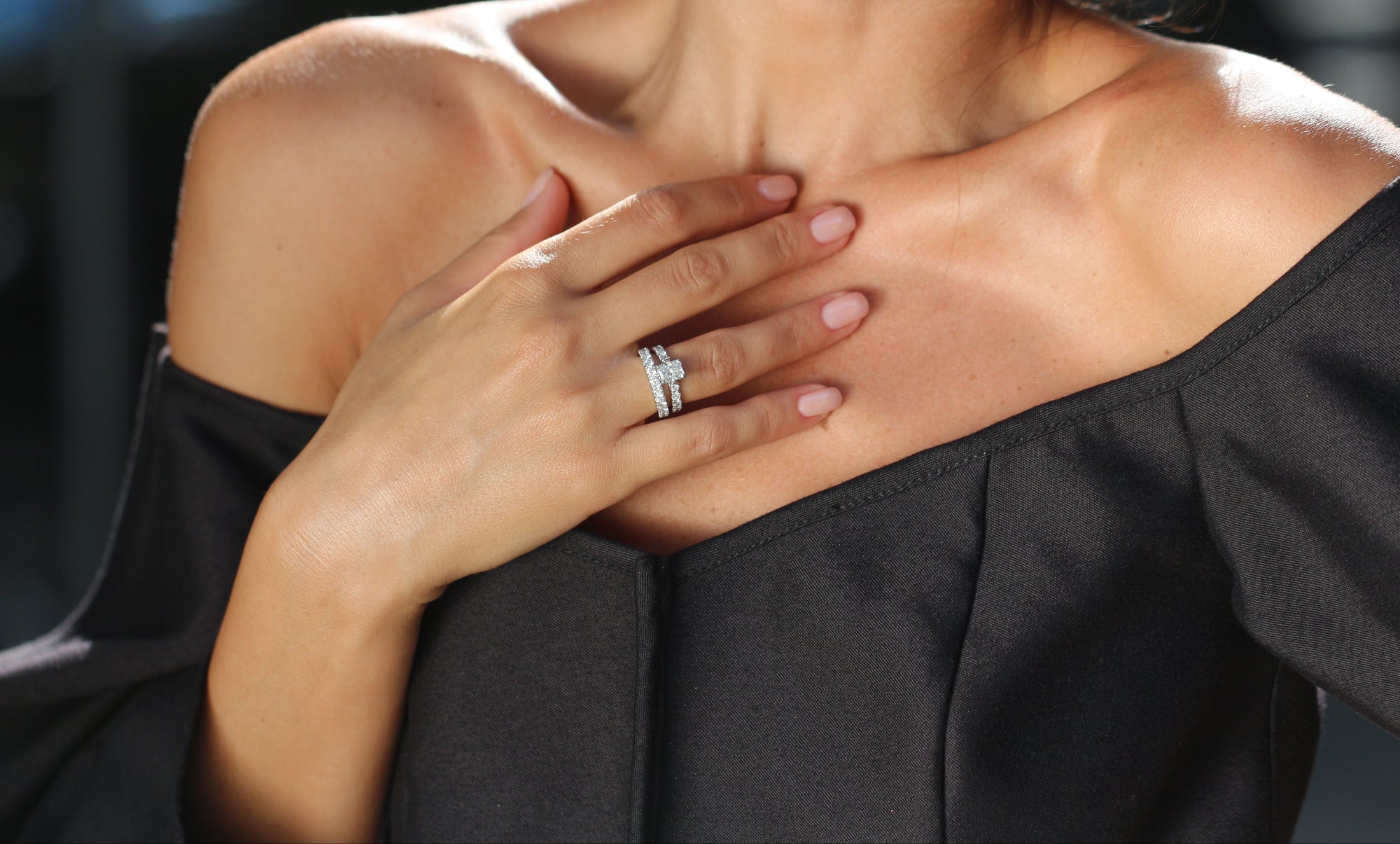 Person wearing a black off-shoulder top with a blurred background