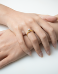 Close-up of hands with a gold ring featuring a pearl on a white background
