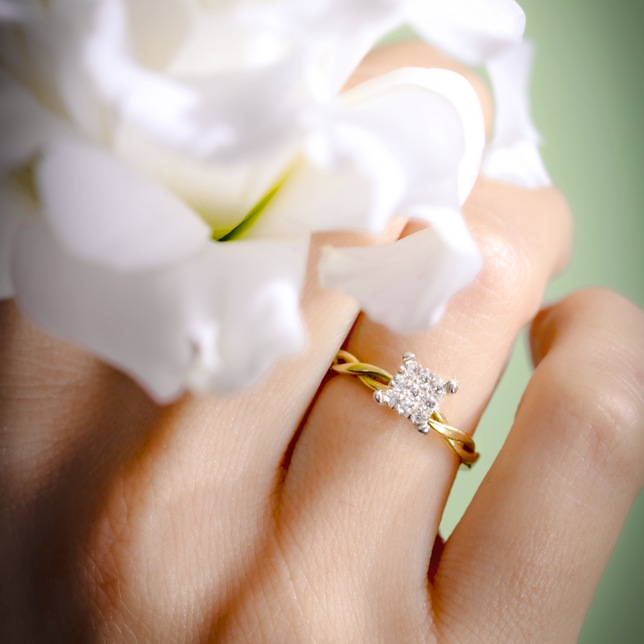Gold ring with a diamond on a hand holding white flowers