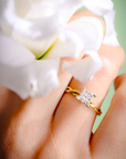 Gold ring with a diamond on a hand holding white flowers