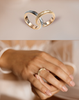 Two gold rings with a blurred hand wearing one of them on a soft beige background