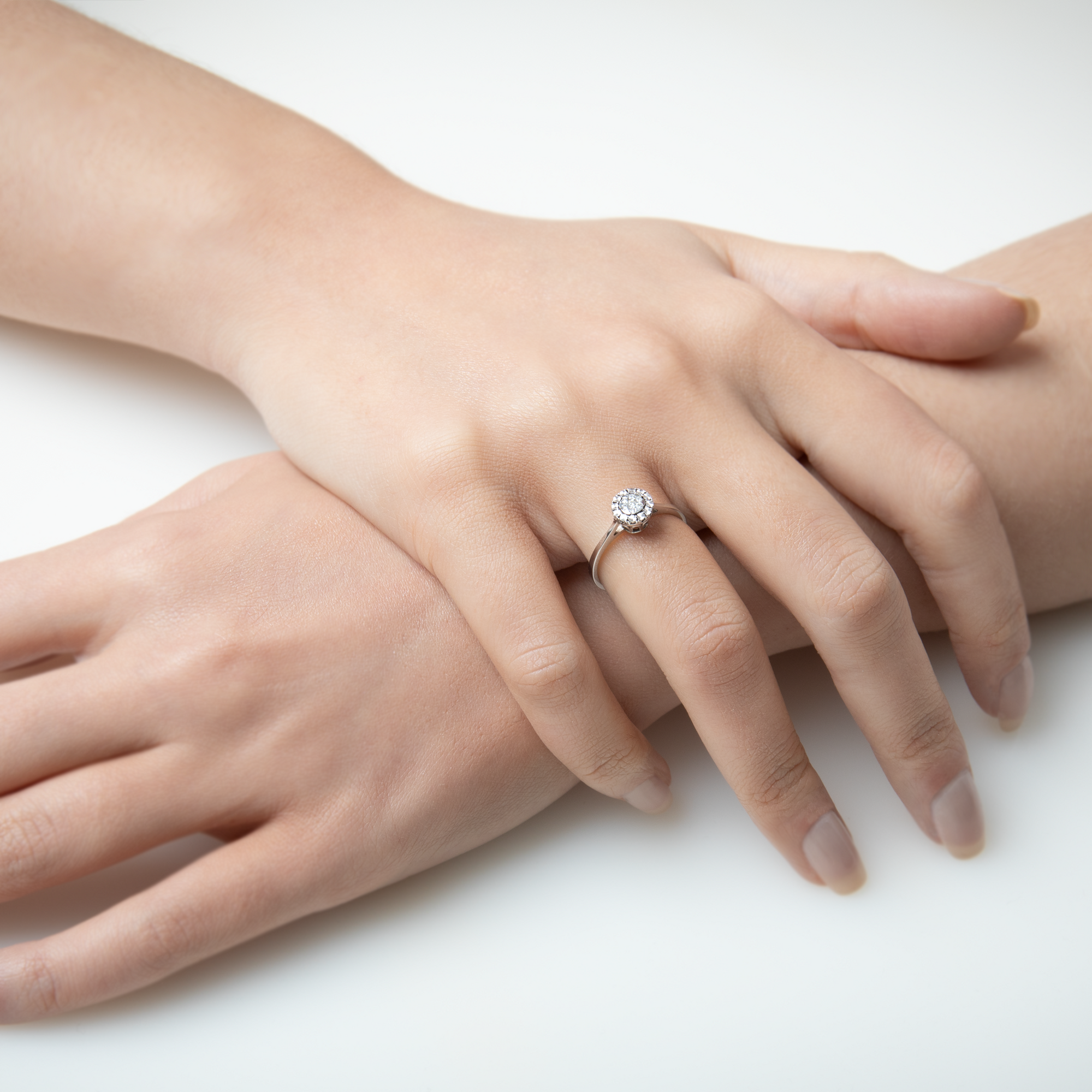 Close-up of a hand wearing a diamond ring on a white background