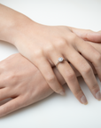 Close-up of a hand wearing a diamond ring on a white background