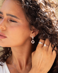 Woman wearing diamond earrings and ring, close-up of face and hand